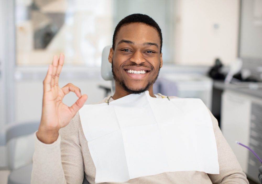 happy-black-male-patient-sitting-in-dentist-chair-and-showing-ok-sign.jpg
